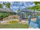 Backyard with a screened pool area, pond with waterfall feature and lush landscaping at 2551 Cross Country Dr, Port Orange, FL 32128