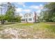 Two-story home with white siding, metal roof, brick chimney, and green trim surrounded by mature trees at 257 Huntington Dr, Deland, FL 32724