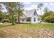 Home exterior featuring white siding, a metal roof, and green trim surrounded by mature trees at 257 Huntington Dr, Deland, FL 32724