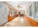 Sunlit living room with hardwood floors, wood trim, classic ceiling fan, and large windows at 257 Huntington Dr, Deland, FL 32724