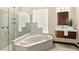 Luxurious bathroom featuring a marble soaking tub, glass shower, and a modern vanity with a wood cabinet at 2636 S Peninsula Dr, Daytona Beach, FL 32118