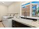Bright laundry room featuring granite countertops, a modern sink, and a view of the home exterior at 2636 S Peninsula Dr, Daytona Beach, FL 32118