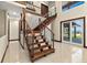 Bright foyer features open staircase with wood treads and stone accent wall; glass doors overlook backyard and waterfront at 2636 S Peninsula Dr, Daytona Beach, FL 32118
