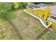 Aerial shot of a sunny, fenced backyard with lawn, landscaping, and a vibrant yellow house at 2940 Se 23Rd Ave, Ocala, FL 34471