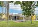 A backyard view of a caged pool with a fenced yard, featuring lush green grass and mature trees at 2940 Se 23Rd Ave, Ocala, FL 34471