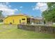 This backyard features a screened pool, wooden fence, lush greenery and a vibrant yellow home at 2940 Se 23Rd Ave, Ocala, FL 34471