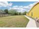A backyard with green grass and a walkway and a wooden fence on a sunny day with scattered clouds at 2940 Se 23Rd Ave, Ocala, FL 34471