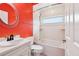 Bathroom featuring an orange accent wall, a shower/tub with a white tiled backsplash, and a circular mirror at 2940 Se 23Rd Ave, Ocala, FL 34471