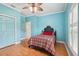 Light-blue bedroom with wood-look floors, two shuttered windows, ceiling fan and floral accents at 2940 Se 23Rd Ave, Ocala, FL 34471