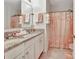 Well-lit bathroom with double granite vanity, peach shower curtain and tile flooring at 316 Nowell Loop, Deland, FL 32724