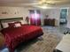 Spacious primary bedroom featuring wood-look floors and a large bed with red bedding at 317 Inwood Ave, New Smyrna Beach, FL 32168