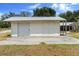 Close-up of a white outbuilding with roll-up door and double doors, adjacent to a house with a screened-in porch at 4145 Rambler Ave, St Cloud, FL 34772