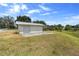 White outbuilding featuring a roll-up door and double doors situated in a grassy yard on a sunny day at 4145 Rambler Ave, St Cloud, FL 34772