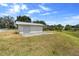 White outbuilding featuring a roll-up door and double doors situated in a grassy yard on a sunny day at 4145 Rambler Ave, St Cloud, FL 34772