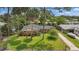 Aerial view of a well-maintained property with lush landscaping, a driveway, and mature trees at 44 Fairway Cir, New Smyrna Beach, FL 32168