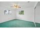 A clean bedroom features a ceiling fan, window with natural light, and a neutral color scheme at 44 Fairway Cir, New Smyrna Beach, FL 32168