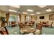 Comfortable common area with multiple round tables, wicker chairs, and natural light from windows at 4670 Links Village Dr # A506, Ponce Inlet, FL 32127