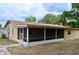 A screened in back porch with a tan facade and a concrete tile patio at 522 Grace Ave, Deland, FL 32724