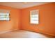 A bedroom with orange walls, tile floors, two windows, and white trim at 522 Grace Ave, Deland, FL 32724