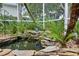 Relaxing screened-in porch features a rock-lined koi pond and lush landscaping at 5776 White Acres Ln, Port Orange, FL 32127