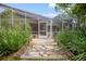 Stone pathway leads to the screened-in porch entrance surrounded by landscaping at 5776 White Acres Ln, Port Orange, FL 32127