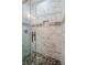 Close-up of shower with pebble floor and patterned white tile walls at 707 Hamilton St, New Smyrna Beach, FL 32168