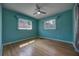 Tranquil turquoise bedroom featuring hardwood floors, ceiling fan, and natural light from two windows at 738 Lindley Blvd, Deland, FL 32724