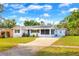 Charming single-story home with a well-manicured lawn, blue door, and solar panels under a bright blue sky at 738 Lindley Blvd, Deland, FL 32724