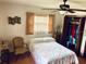 Inviting bedroom with a ceiling fan, closet, and comfortable bed complemented by a vintage chair at 7380 Orange Ave, Indian Lake Estates, FL 33855