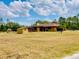 Expansive property featuring the house and two sheds with lush green lawn and trees at 7380 Orange Ave, Indian Lake Estates, FL 33855