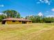Sprawling lawn complements this single-story home, set against a backdrop of lush greenery and a clear blue sky at 7380 Orange Ave, Indian Lake Estates, FL 33855