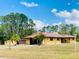 Well-maintained single story home with a red tile roof, outbuildings, and mature trees in a serene neighborhood setting at 7380 Orange Ave, Indian Lake Estates, FL 33855