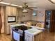Kitchen with island cooktop, microwave, adjacent laundry area, and wood flooring at 7380 Orange Ave, Indian Lake Estates, FL 33855