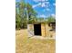 A small shed for extra storage sits on a property with mature trees and blue skies at 7380 Orange Ave, Indian Lake Estates, FL 33855