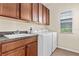 Well-equipped laundry room with upper cabinets, countertop sink, and modern, white front-loading washer and dryer at 8832 Ribault Ave, Orlando, FL 32832