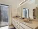 Bathroom with double vanity sinks, large mirror, and a sliding door to the outside at 907 Silver Leaf Pl, Port Orange, FL 32127
