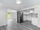 Open kitchen and dining area with updated cabinets, stainless steel refrigerator, and gray wood flooring at 102 Judges Ln, Port Orange, FL 32129
