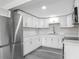 Bright kitchen featuring white cabinets, subway tile backsplash, stainless steel appliances, and modern gray wood flooring at 102 Judges Ln, Port Orange, FL 32129