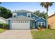 Charming two-story blue home with a manicured lawn, a brick driveway, and a two-car garage at 109 Fern Springs St, Debary, FL 32713