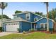 Charming two-story blue home with a manicured lawn, a brick driveway, and a two-car garage at 109 Fern Springs St, Debary, FL 32713