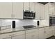 Close-up of a kitchen featuring sleek stainless steel appliances, granite countertops, and modern white cabinetry at 165 Azure Mist Way, Daytona Beach, FL 32124