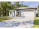 Well-lit exterior of a single-Gathering home featuring a spacious driveway leading to a two-car garage at 1738 Palm Rd, Ormond Beach, FL 32174