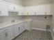 Laundry room features white cabinets, quartz countertops, modern faucet, and mosaic tile floors at 1870 Pepper Tree Ln, Deland, FL 32720
