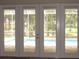 The back patio offers a view of the blue pool, yard, and the trees beyond for outdoor enjoyment at 1870 Pepper Tree Ln, Deland, FL 32720