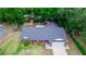 Aerial view of a brick home with a dark roof, a well-manicured lawn, and mature trees in a neighborhood at 20 Monroe Ave, Debary, FL 32713