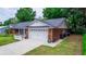 Side view of a brick home featuring manicured lawn, mature trees, and a two-car garage at 20 Monroe Ave, Debary, FL 32713