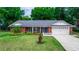 Charming brick home featuring a manicured lawn, mature trees, and a two-car garage at 20 Monroe Ave, Debary, FL 32713