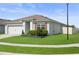 Low angle shot of a single-story home with manicured lawn and garden, two-car garage, and neutral color scheme at 2000 White Pelican Ter, Sanford, FL 32771