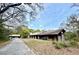 Exterior view of a rustic house with a long driveway, trees, and lush front yard at 2068 Pennsylvania Dr, Deland, FL 32724
