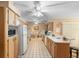 Bright, open kitchen with oak cabinets, white appliances, and tile flooring leading to a dining area at 2287 Belen Dr, Deltona, FL 32738